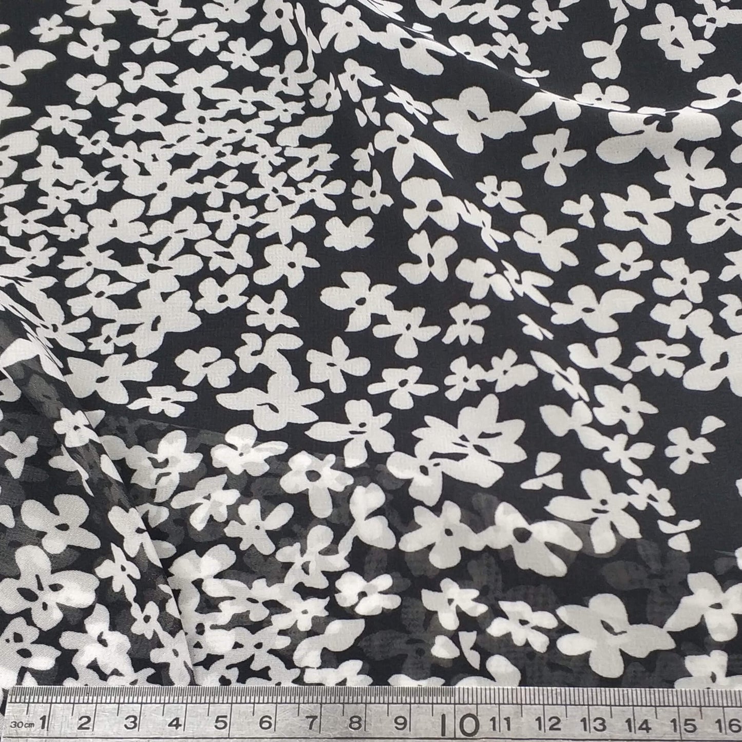 Floral patterned chiffon fabric with white flowers on a black background