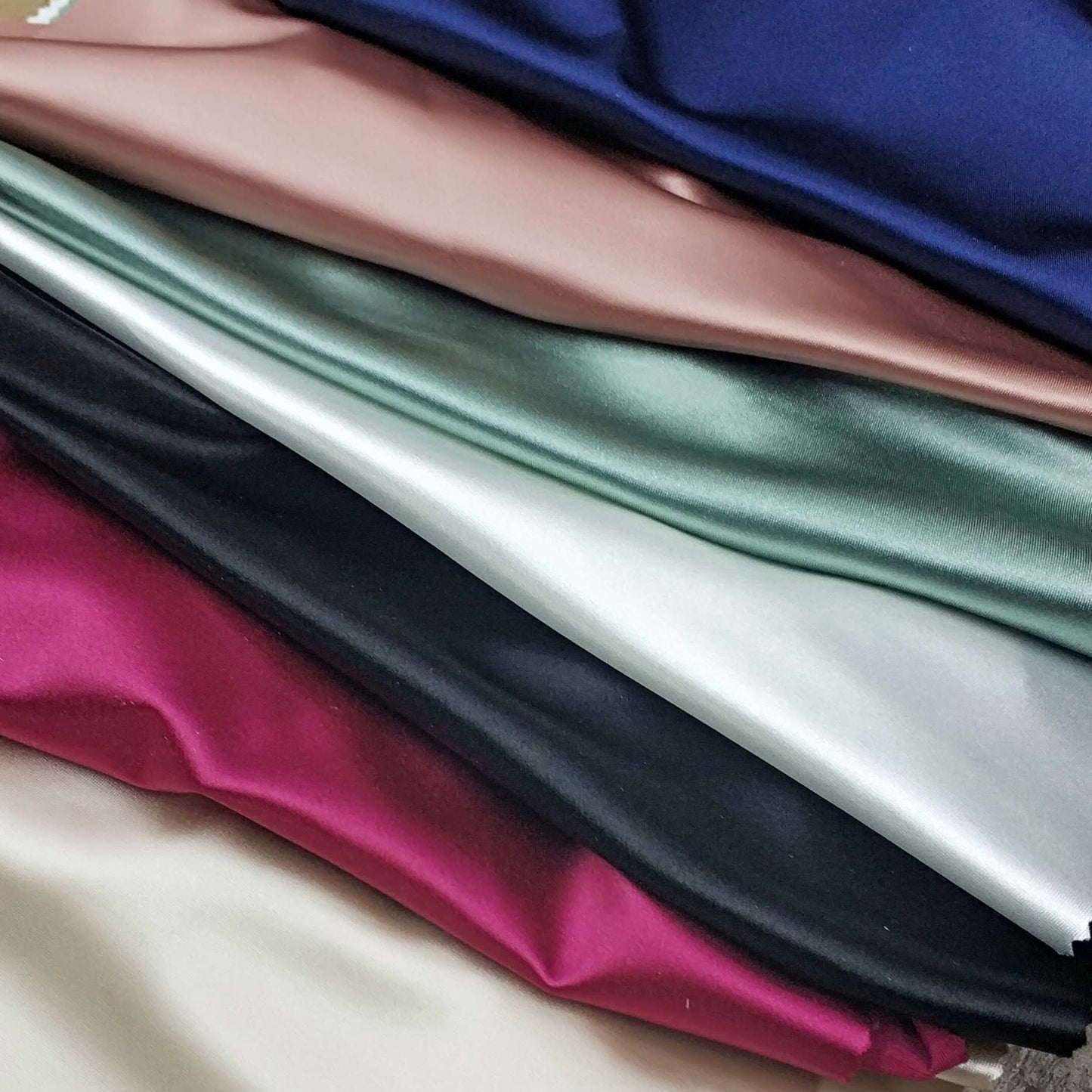 Collection Of Folded Satin Fabric In Various Colors.