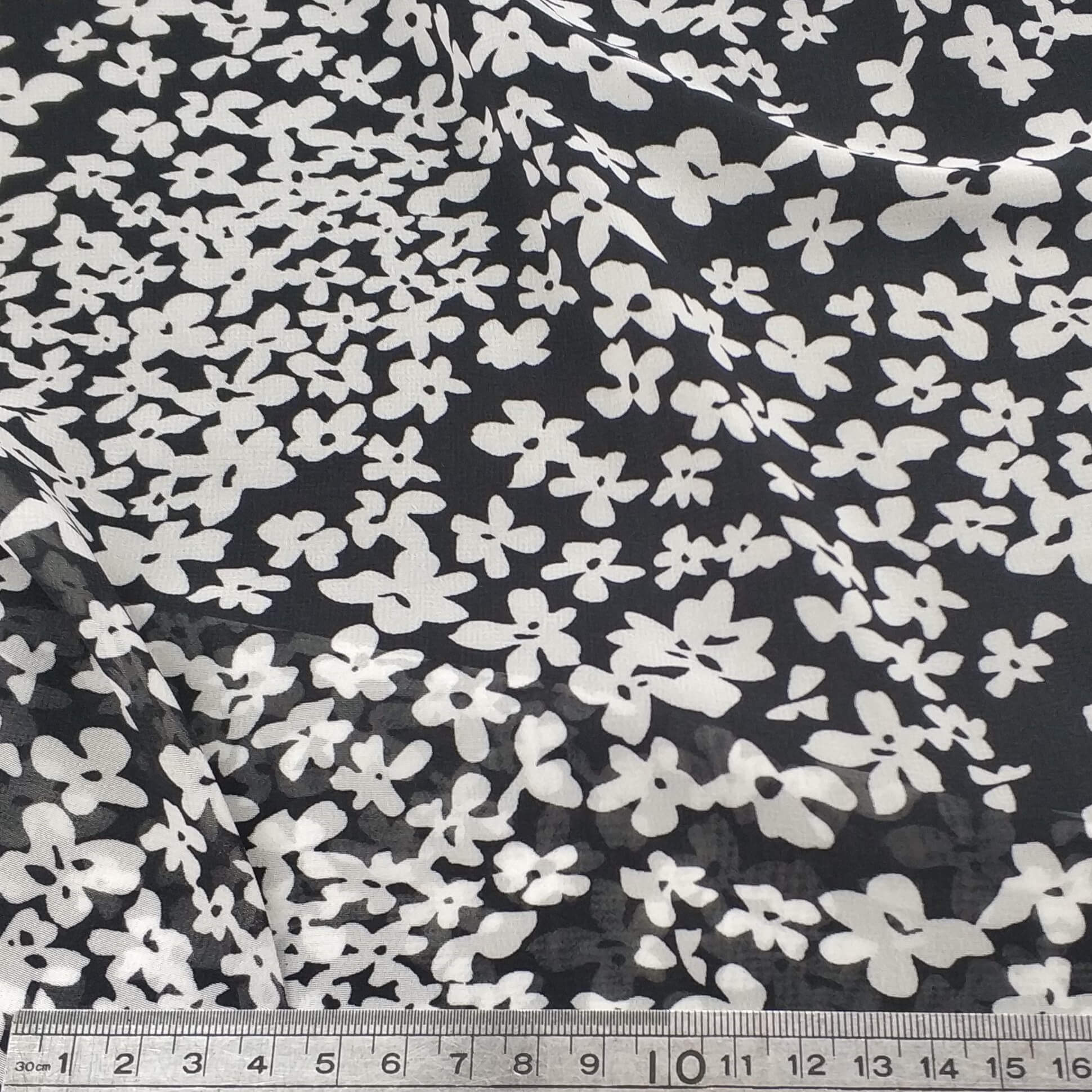 Floral patterned chiffon fabric with white flowers on a black background