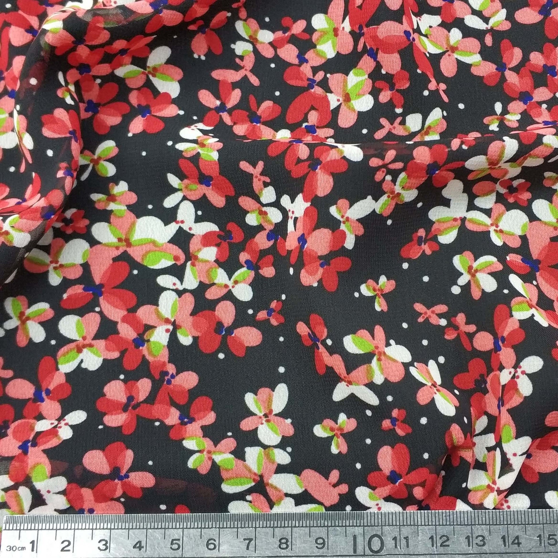 Floral chiffon fabric with red and pink flowers on a black background.