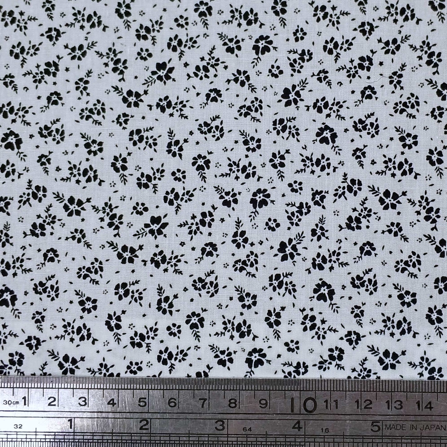 Floral patterned fabric, small black flowers on a white backround.