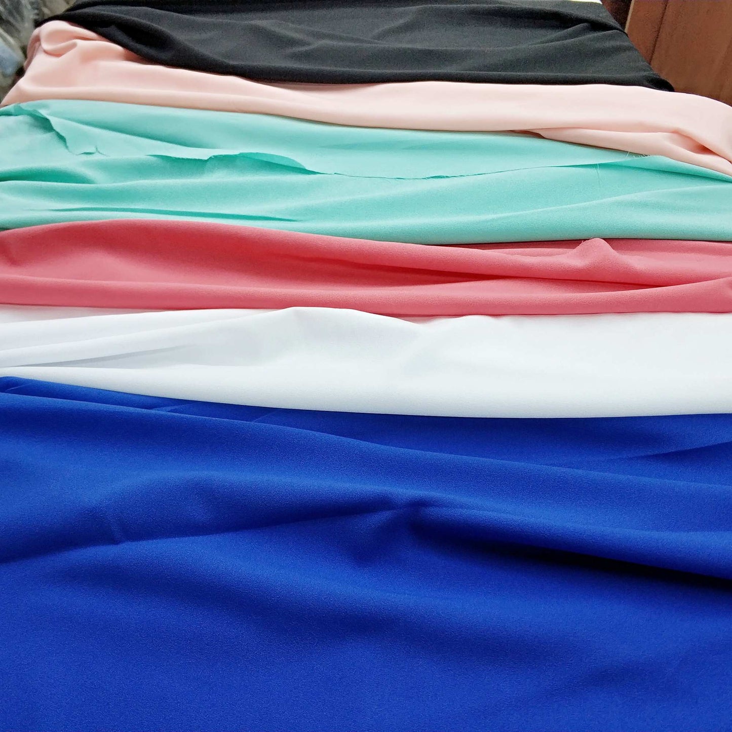 Stack of colorful fabrics including blue, pink, white, and green.