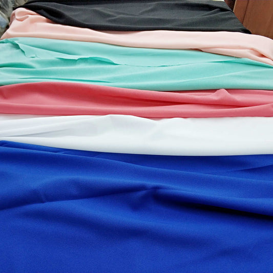 Stack of colorful fabrics including blue, pink, white, and green.