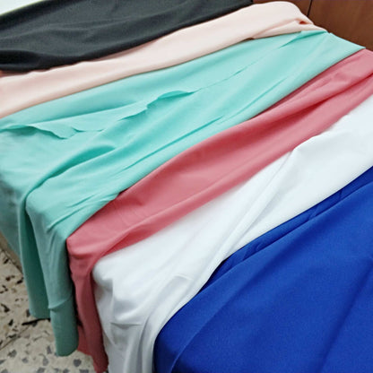 Stack of colorful fabrics in various colors including blue, pink, green, and white.