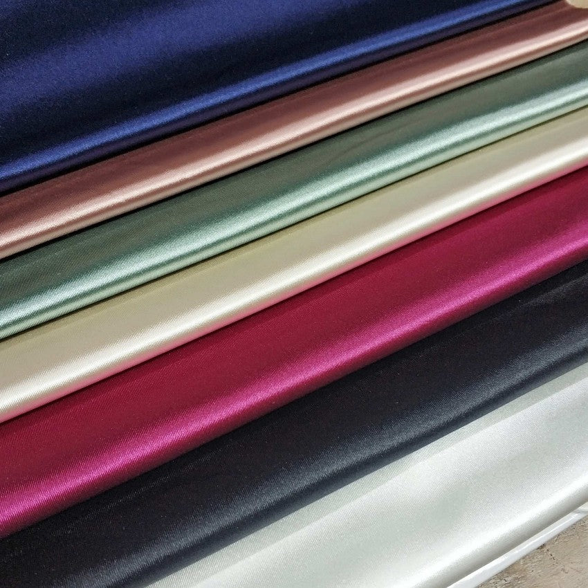 Stack of colorful satin fabric in various shades.